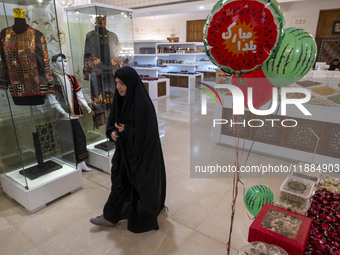 A veiled Iranian woman walks past Yalda Night decorations while visiting the Iran Mall shopping mall in northwestern Tehran, Iran, on Decemb...