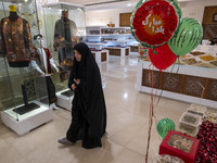 A veiled Iranian woman walks past Yalda Night decorations while visiting the Iran Mall shopping mall in northwestern Tehran, Iran, on Decemb...