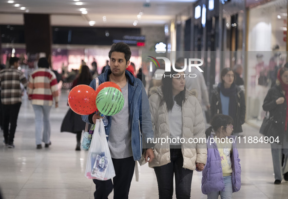 An Iranian man carries watermelon-shaped balloons as he walks with his family at the Iran Mall shopping mall in northwestern Tehran, Iran, o...