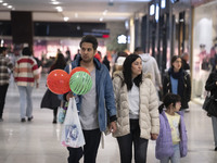 An Iranian man carries watermelon-shaped balloons as he walks with his family at the Iran Mall shopping mall in northwestern Tehran, Iran, o...