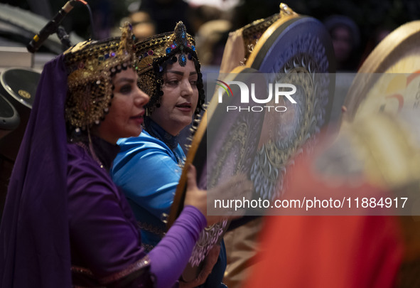 Two women wearing Iranian traditional dresses play traditional musical instruments during Yalda Night celebrations at the Iran Mall shopping...