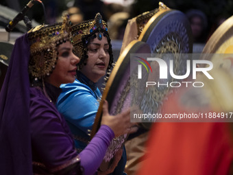 Two women wearing Iranian traditional dresses play traditional musical instruments during Yalda Night celebrations at the Iran Mall shopping...