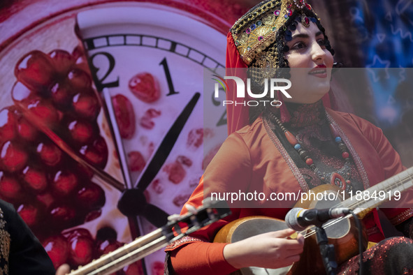 A young woman wearing an Iranian traditional dress plays a traditional musical instrument during Yalda Night celebrations at the Iran Mall s...