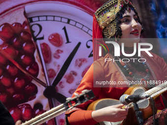 A young woman wearing an Iranian traditional dress plays a traditional musical instrument during Yalda Night celebrations at the Iran Mall s...