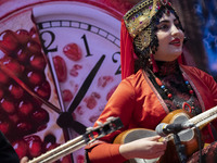 A young woman wearing an Iranian traditional dress plays a traditional musical instrument during Yalda Night celebrations at the Iran Mall s...