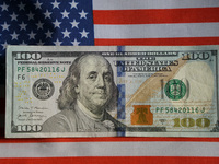 U.S. dollars and a U.S. flag are seen in Shanghai, China, on December 21, 2024. (