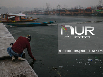 An Indian tourist attempts to break the partially frozen waters of Dal Lake in Srinagar, Jammu and Kashmir, on December 21, 2024. The 40-day...