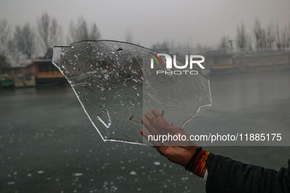 A man displays ice sheets of partially frozen waters of Dal Lake in Srinagar, Jammu and Kashmir, on December 21, 2024. The 40-day harsh wint...