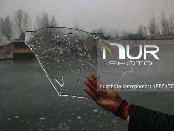 A man displays ice sheets of partially frozen waters of Dal Lake in Srinagar, Jammu and Kashmir, on December 21, 2024. The 40-day harsh wint...