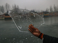 A man displays ice sheets of partially frozen waters of Dal Lake in Srinagar, Jammu and Kashmir, on December 21, 2024. The 40-day harsh wint...