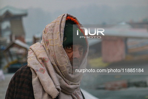 A man covers his head with a scarf as he sits on the banks of Dal Lake in Srinagar, Jammu and Kashmir, on December 21, 2024. The 40-day hars...