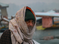 A man covers his head with a scarf as he sits on the banks of Dal Lake in Srinagar, Jammu and Kashmir, on December 21, 2024. The 40-day hars...