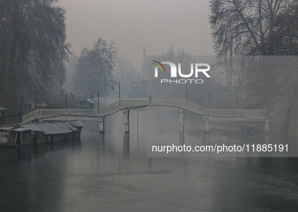 A man walks over a wooden bridge in Srinagar, Jammu and Kashmir, on December 21, 2024. The 40-day harsh winter period, locally referred to a...