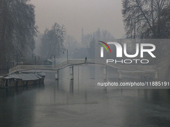 A man walks over a wooden bridge in Srinagar, Jammu and Kashmir, on December 21, 2024. The 40-day harsh winter period, locally referred to a...