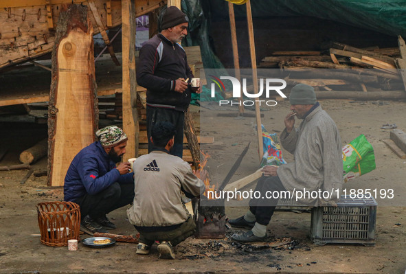 People warm themselves around a bonfire on a cold morning in Srinagar, Jammu and Kashmir, on December 21, 2024. The 40-day harsh winter peri...