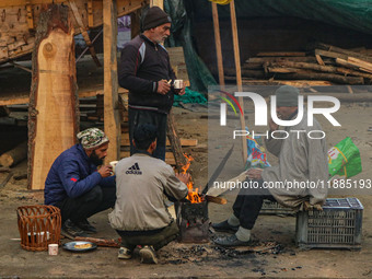 People warm themselves around a bonfire on a cold morning in Srinagar, Jammu and Kashmir, on December 21, 2024. The 40-day harsh winter peri...