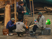 People warm themselves around a bonfire on a cold morning in Srinagar, Jammu and Kashmir, on December 21, 2024. The 40-day harsh winter peri...