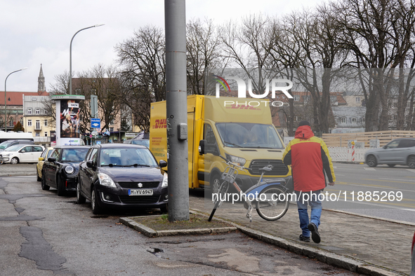 A DHL delivery vehicle parks in a residential area in Munich, Bavaria, Germany, on December 20, 2024 