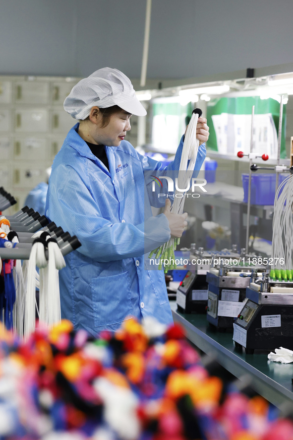 A worker produces photoelectric cables for export at a workshop of a communication equipment company in the Sihong Economic Development Zone...