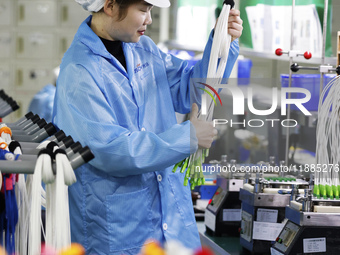 A worker produces photoelectric cables for export at a workshop of a communication equipment company in the Sihong Economic Development Zone...