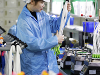 A worker produces photoelectric cables for export at a workshop of a communication equipment company in the Sihong Economic Development Zone...