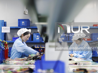 Workers produce photoelectric cables for export at a workshop of a company that produces communication equipment in the Sihong Economic Deve...