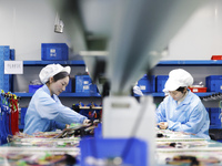 Workers produce photoelectric cables for export at a workshop of a company that produces communication equipment in the Sihong Economic Deve...