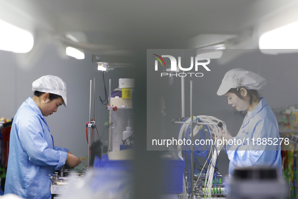 Workers produce photoelectric cables for export at a workshop of a company that produces communication equipment in the Sihong Economic Deve...