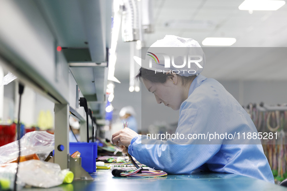 A worker produces photoelectric cables for export at a workshop of a communication equipment company in the Sihong Economic Development Zone...