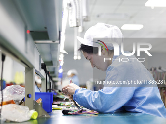 A worker produces photoelectric cables for export at a workshop of a communication equipment company in the Sihong Economic Development Zone...