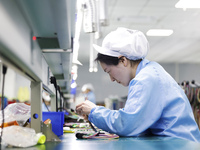 A worker produces photoelectric cables for export at a workshop of a communication equipment company in the Sihong Economic Development Zone...