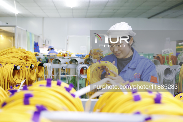 A worker produces photoelectric cables for export at a workshop of a communication equipment company in the Sihong Economic Development Zone...