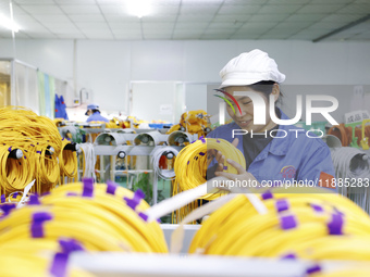 A worker produces photoelectric cables for export at a workshop of a communication equipment company in the Sihong Economic Development Zone...