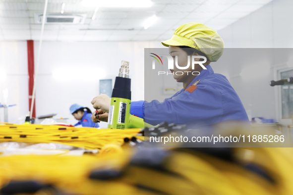 A worker produces photoelectric cables for export at a workshop of a communication equipment company in the Sihong Economic Development Zone...