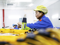 A worker produces photoelectric cables for export at a workshop of a communication equipment company in the Sihong Economic Development Zone...