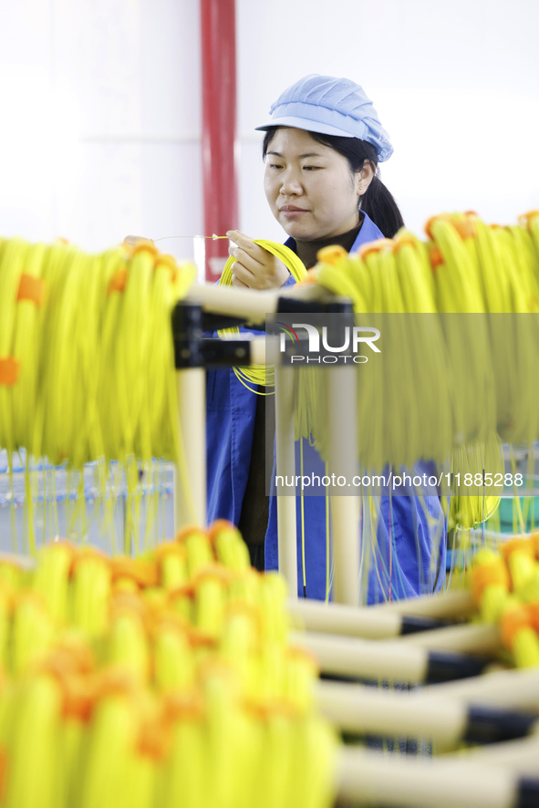 A worker produces photoelectric cables for export at a workshop of a communication equipment company in the Sihong Economic Development Zone...