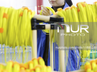 A worker produces photoelectric cables for export at a workshop of a communication equipment company in the Sihong Economic Development Zone...