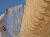 A worker places hanging noodles on a shelf to dry in Hefei, Anhui province, China, on December 21, 2024. (