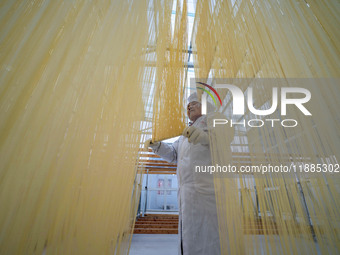 A worker places hanging noodles on a shelf to dry in Hefei, Anhui province, China, on December 21, 2024. (