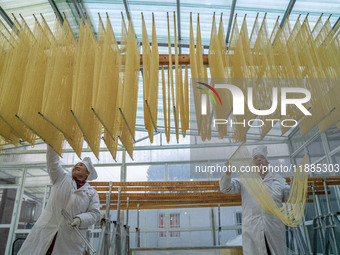 A worker places hanging noodles on a shelf to dry in Hefei, Anhui province, China, on December 21, 2024. (