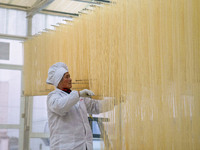 A worker places hanging noodles on a shelf to dry in Hefei, Anhui province, China, on December 21, 2024. (