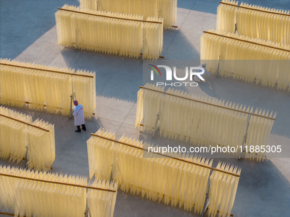 A worker places hanging noodles on a shelf to dry in Hefei, Anhui province, China, on December 21, 2024. 