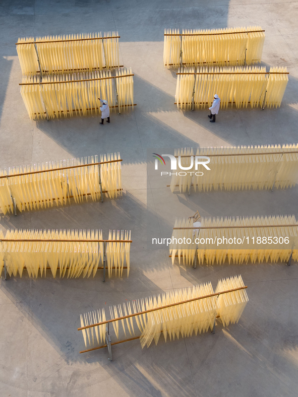 A worker places hanging noodles on a shelf to dry in Hefei, Anhui province, China, on December 21, 2024. 