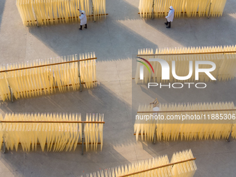 A worker places hanging noodles on a shelf to dry in Hefei, Anhui province, China, on December 21, 2024. (