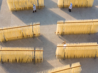 A worker places hanging noodles on a shelf to dry in Hefei, Anhui province, China, on December 21, 2024. (