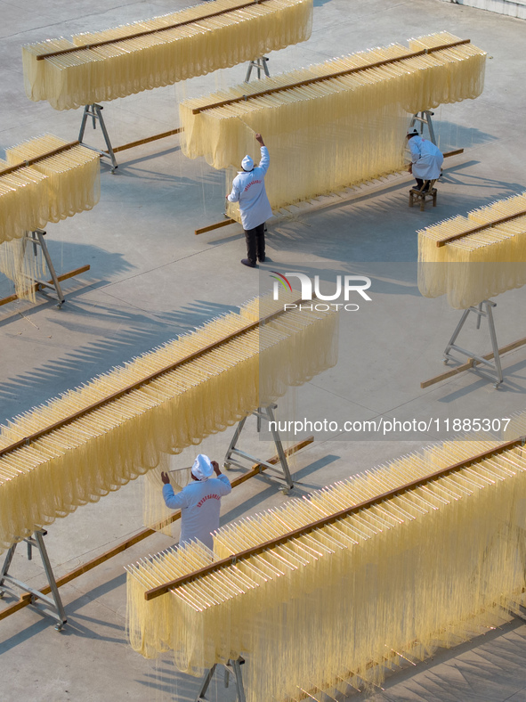 A worker places hanging noodles on a shelf to dry in Hefei, Anhui province, China, on December 21, 2024. 