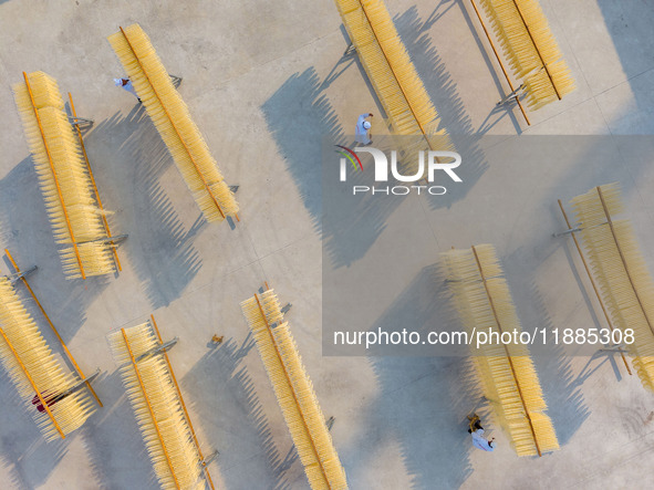 A worker places hanging noodles on a shelf to dry in Hefei, Anhui province, China, on December 21, 2024. 