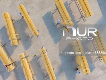 A worker places hanging noodles on a shelf to dry in Hefei, Anhui province, China, on December 21, 2024. (