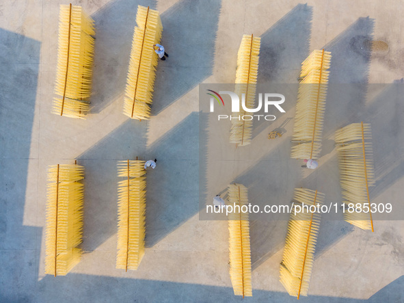 A worker places hanging noodles on a shelf to dry in Hefei, Anhui province, China, on December 21, 2024. 