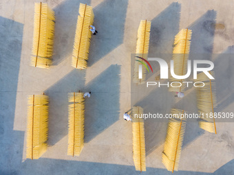 A worker places hanging noodles on a shelf to dry in Hefei, Anhui province, China, on December 21, 2024. (